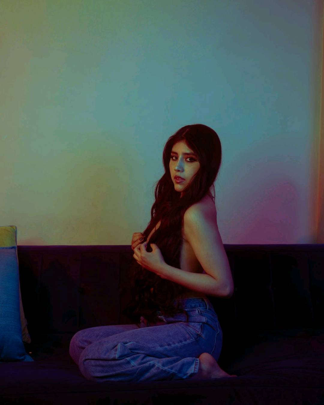 A woman from Bolivia sitting in colored light, open to talk to strangers