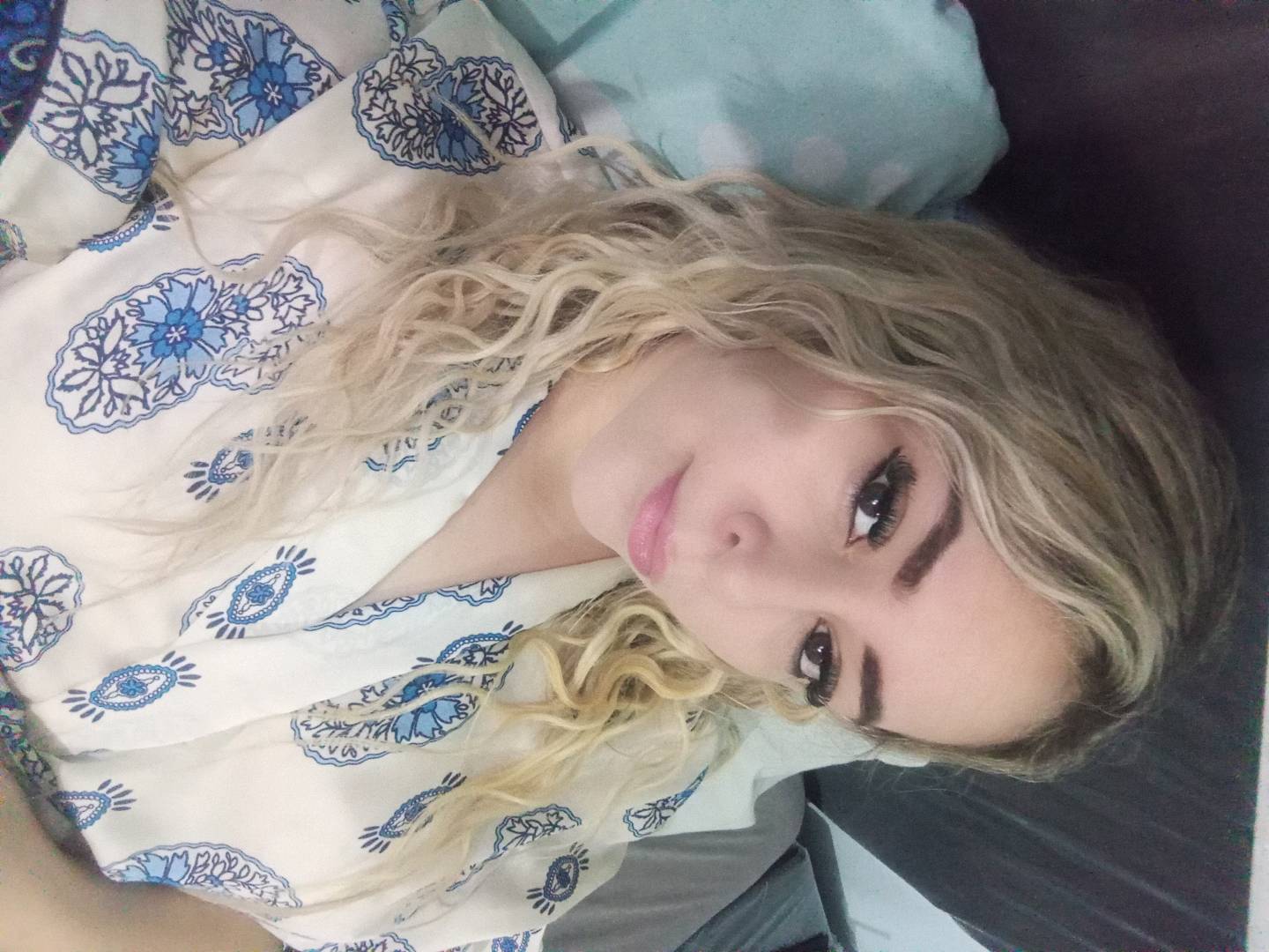 A woman from Paraguay with blonde curls lying back, ready for an Omegle video chat
